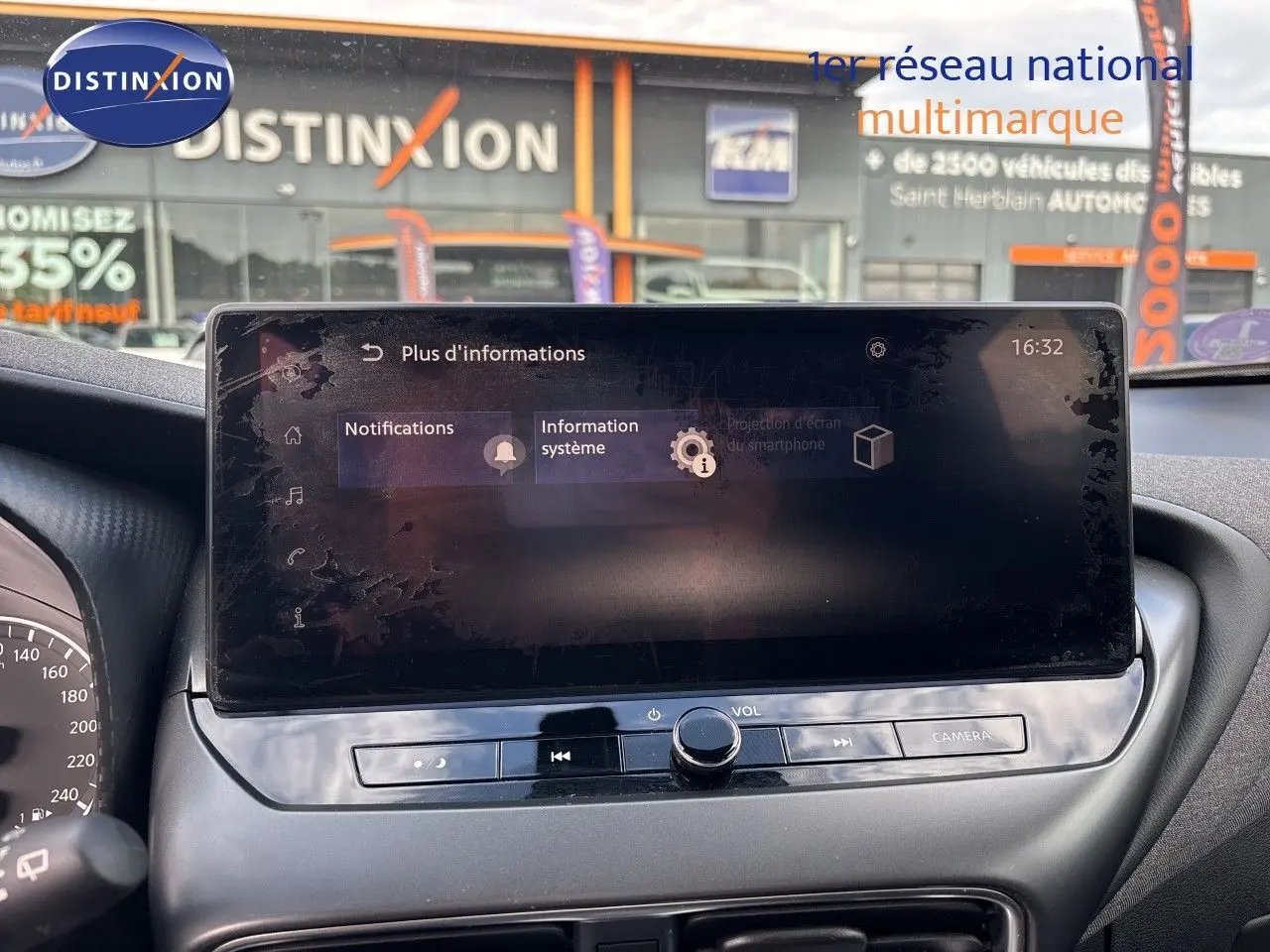 Vue intérieure du tableau de bord du Nissan Juke Hybrid 2024, écran tactile central avec commandes audio et caméra, finition noire.