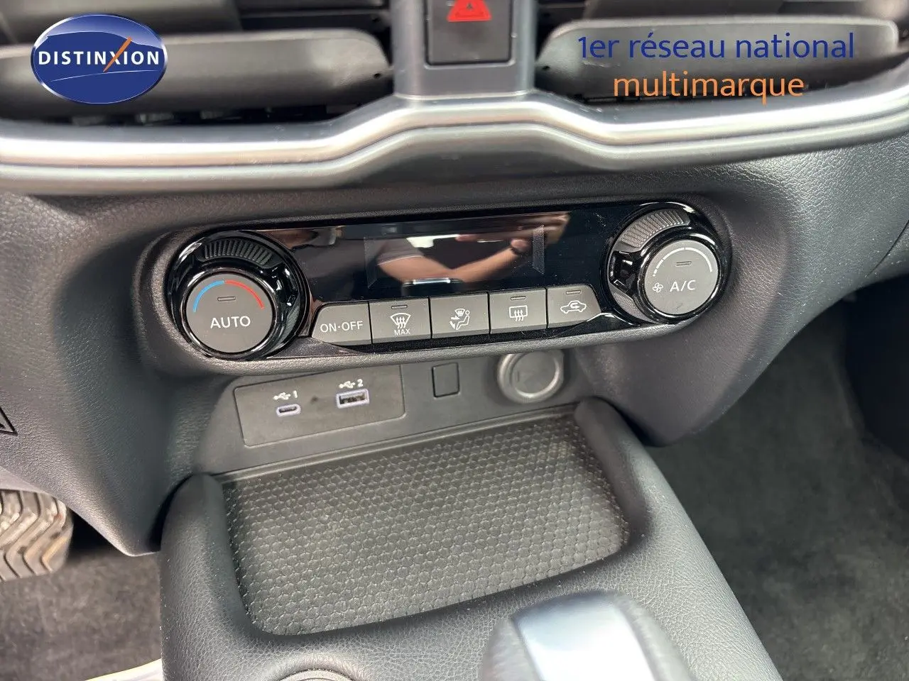 Détail de la console centrale du Nissan Juke Hybrid 2024 avec commandes de climatisation et ports USB visibles.