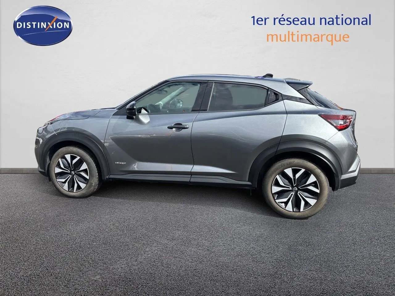 Profil droit du Nissan Juke Hybrid 143ch Business Edition 2024 en gris squale métal avec jantes distinctives bicolores.