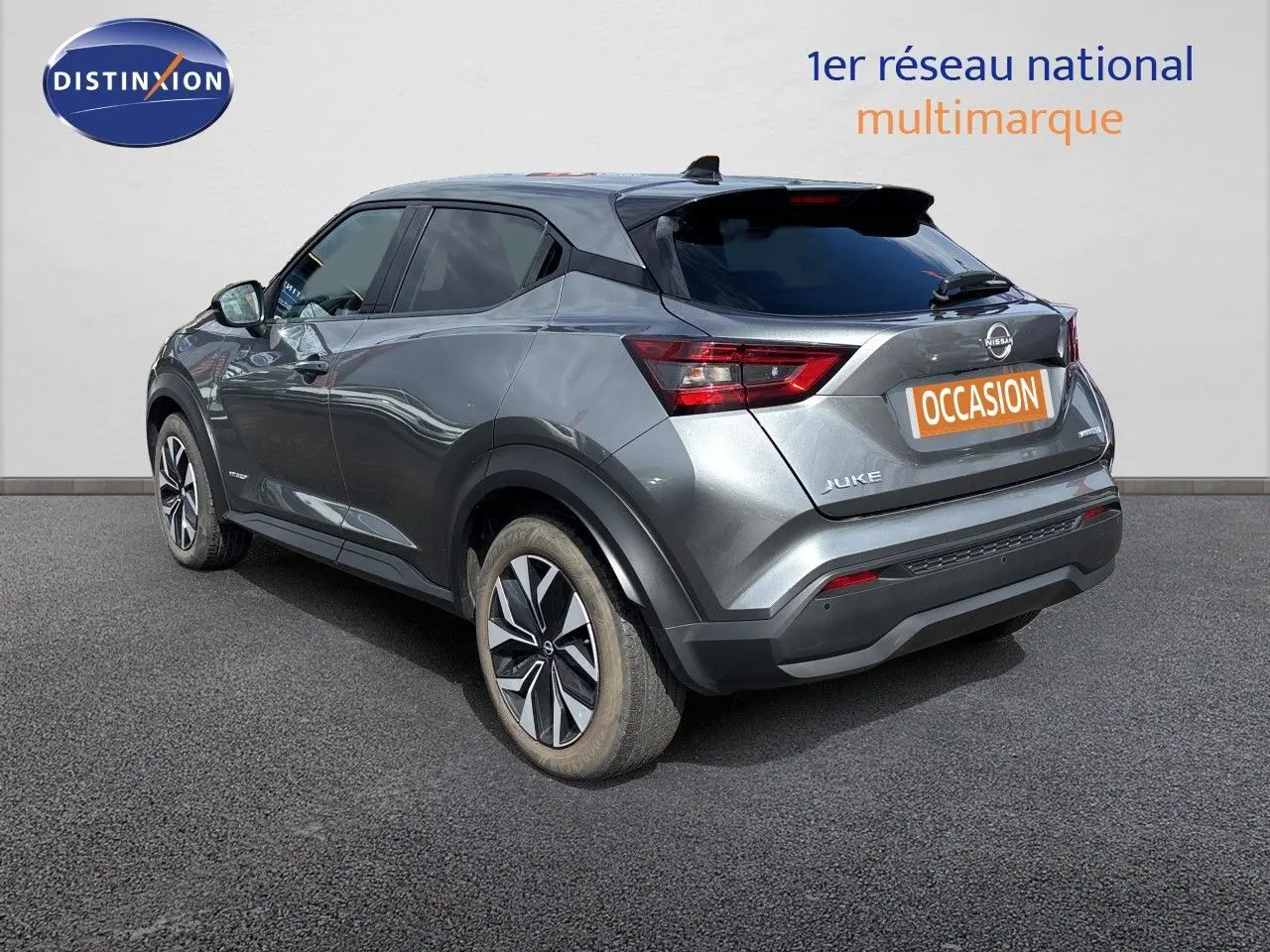 Nissan Juke Hybrid gris squale métal, vue 3/4 arrière droit, avec jantes alliage et feux arrière LED distinctifs.