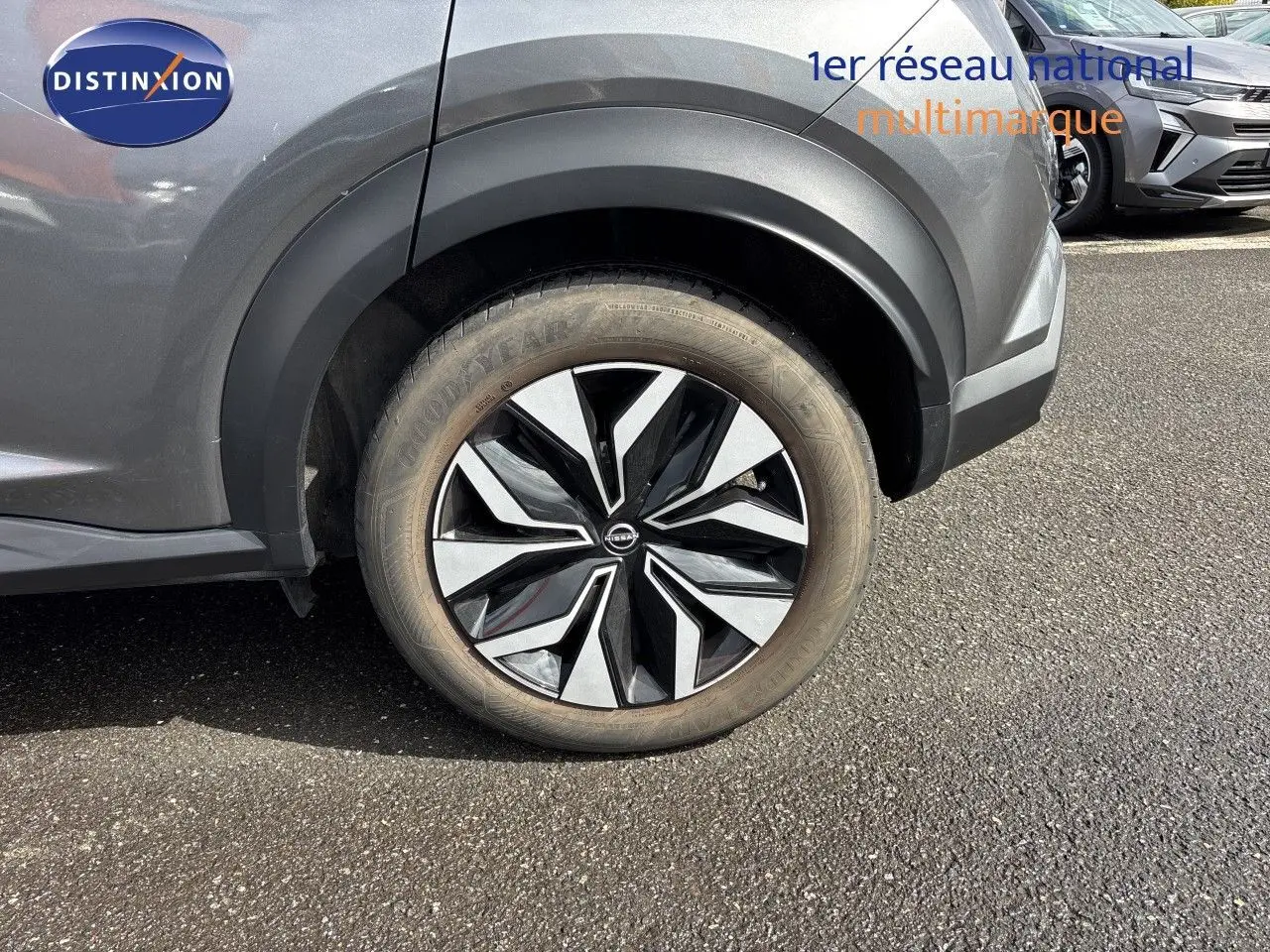 Gros plan sur la roue arrière droite d'un Nissan Juke Hybrid gris squale metal, avec jante noire et argentée design moderne.