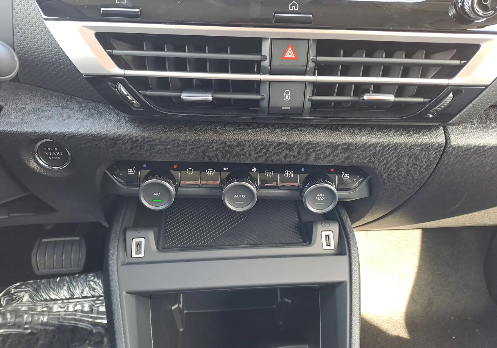 Tableau de bord central de la Citroën C4 hybride 2025, avec commandes climatisation et bouton start/stop visibles.