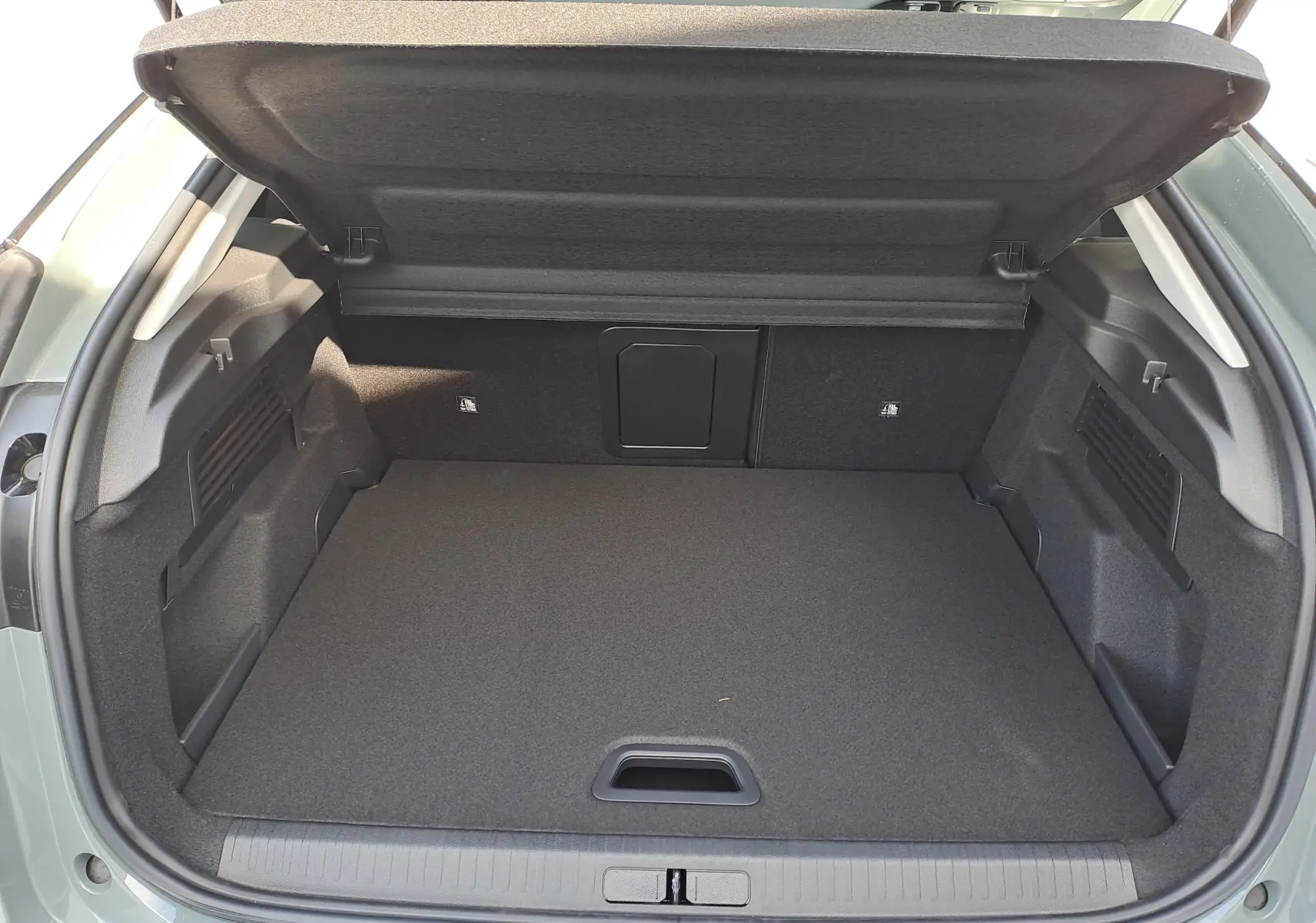 Coffre ouvert vu de l'arrière d'une Citroën C4 hybride 2025 Manhattan Green avec toit noir, intérieur de coffre gris.