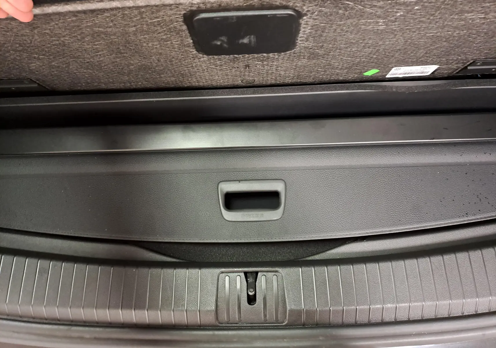 Détail du coffre ouvert du Volkswagen Touran noir Grenadille, montrant la poignée de fermeture et le seuil de chargement.