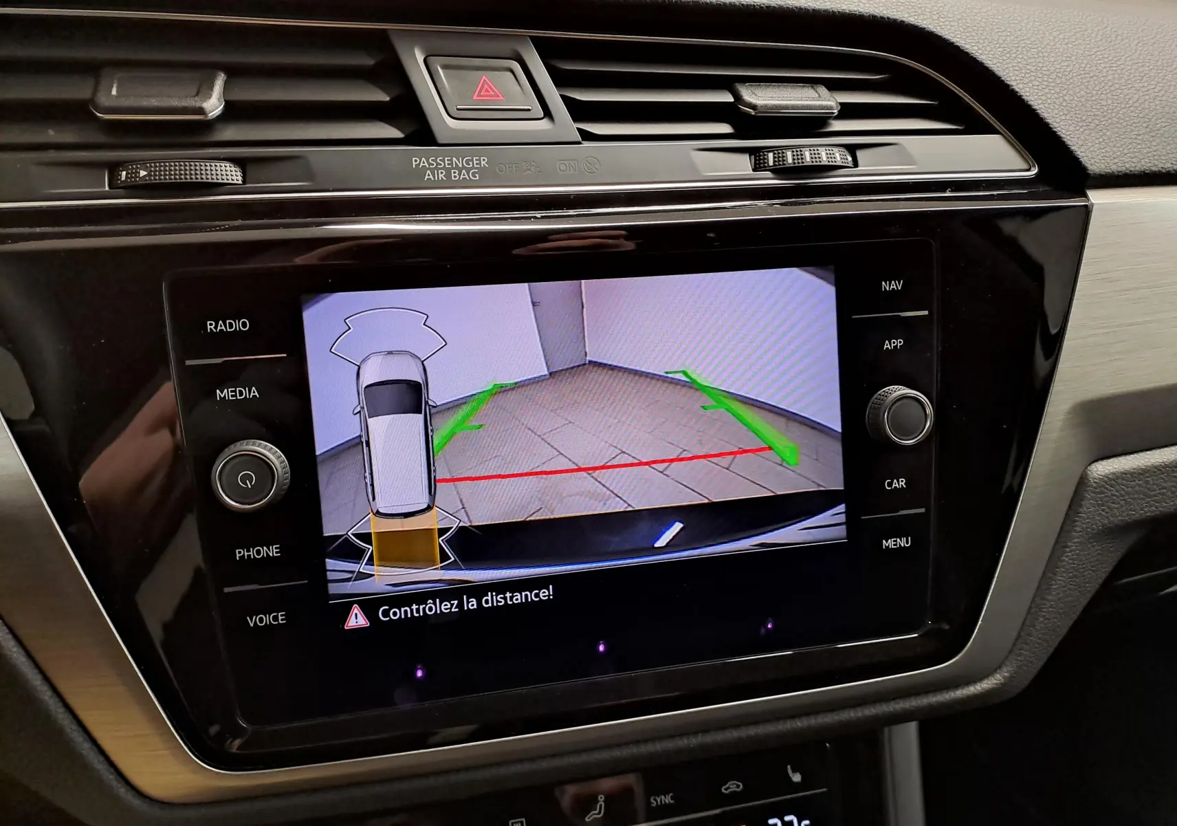 Écran central du Volkswagen Touran 2025 montrant la caméra de recul avec alertes de distance, entouré de commandes multimédia.