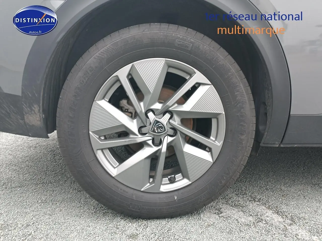 Gros plan sur la jante alu grise et le pneu d'un Peugeot 408 Hybrid 145 allure e-dcs6 gris sellenium e.