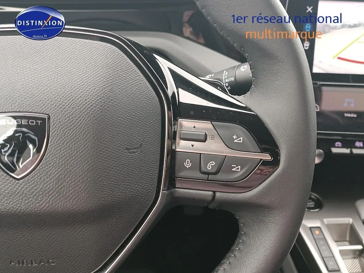 Gros plan sur le volant cuir multifonction de la Peugeot 408 gris sellenium avec commandes audio et vocales visibles.