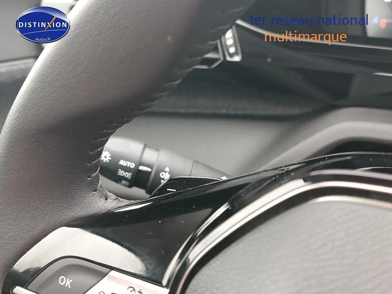 Gros plan sur le volant cuir multifonction noir de la Peugeot 408 Hybrid 145 allure 2024, avec commandes intégrées.