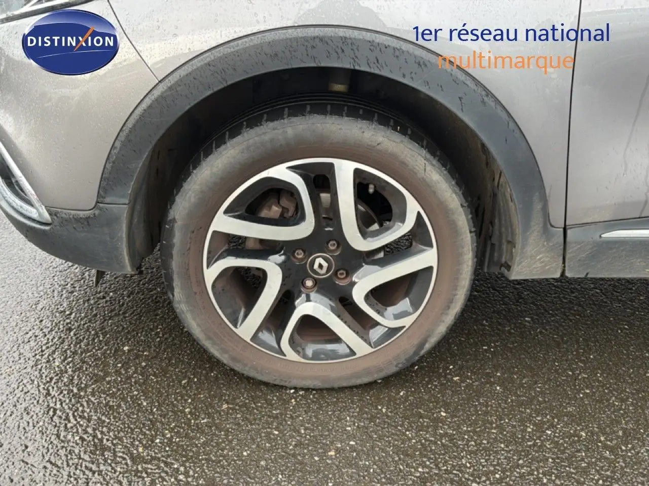 Gros plan sur la roue avant gauche d’un Renault Captur gris Cassiopée avec jante alliage bicolore et logo Renault central.