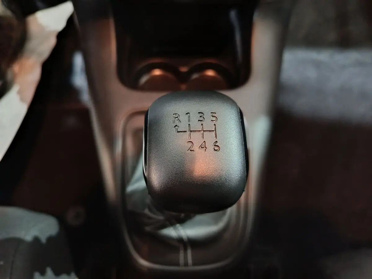 Gros plan sur le levier de vitesses manuel noir de la Citroën C3 BlueHDi 100, intérieur sombre.