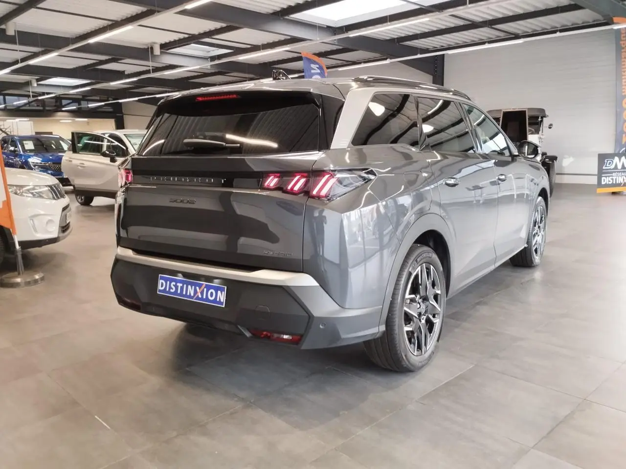 Vue 3/4 arrière droite d’un Peugeot 5008 gris titanium avec feux arrière LED 3 griffes et jantes alliage 19 pouces.