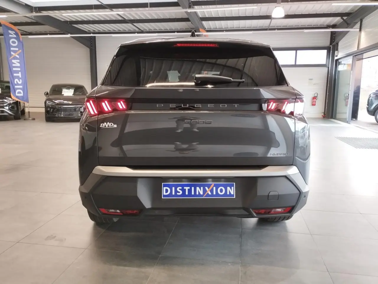 Vue arrière d’un Peugeot 5008 gris titanium avec feux arrière à LED en forme de griffes dans un showroom.