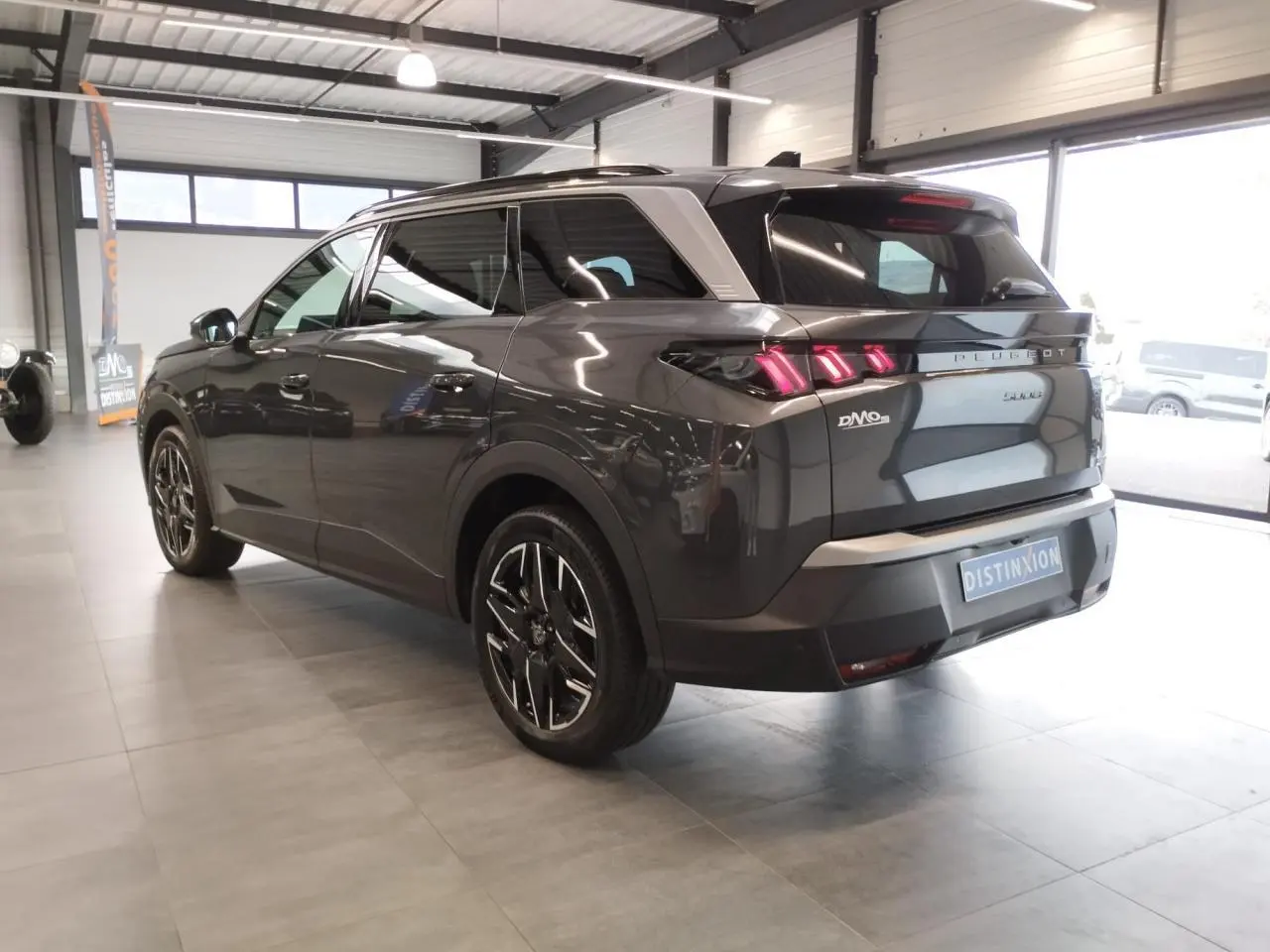 Vue 3/4 arrière droit d’un Peugeot 5008 gris titanium avec feux arrière à LED en forme de griffes et jantes alliage noires.