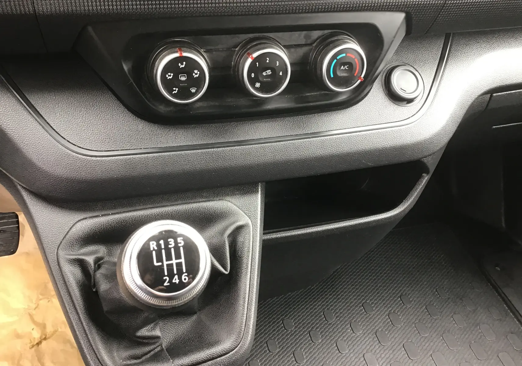 Gros plan sur la console centrale du Renault Trafic Combi 2022, montrant le levier de vitesse manuel et les commandes de climatisation.