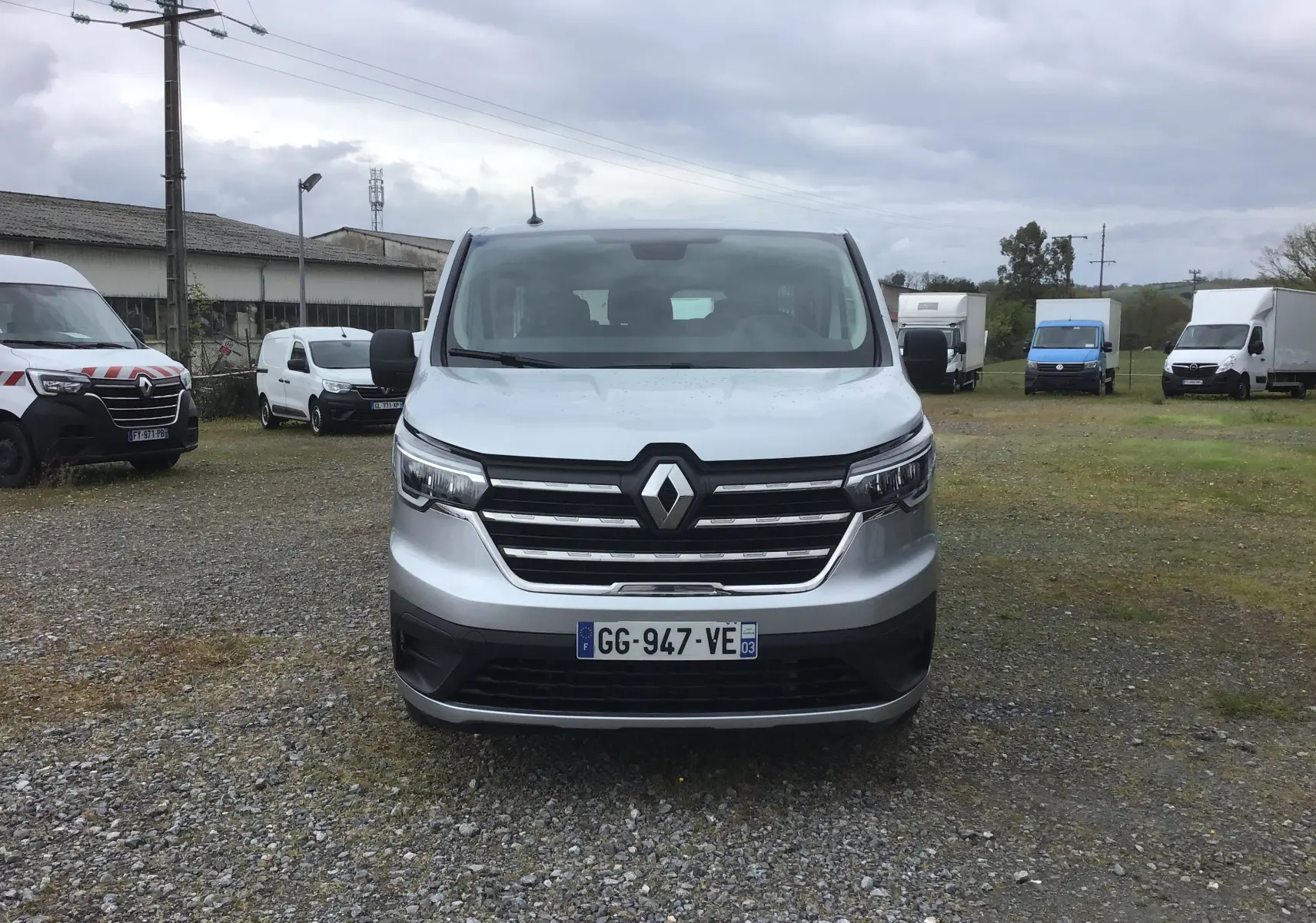 Vue de face d'un Renault Trafic Combi gris clair métal, avec calandre chromée et logo Renault bien visible.