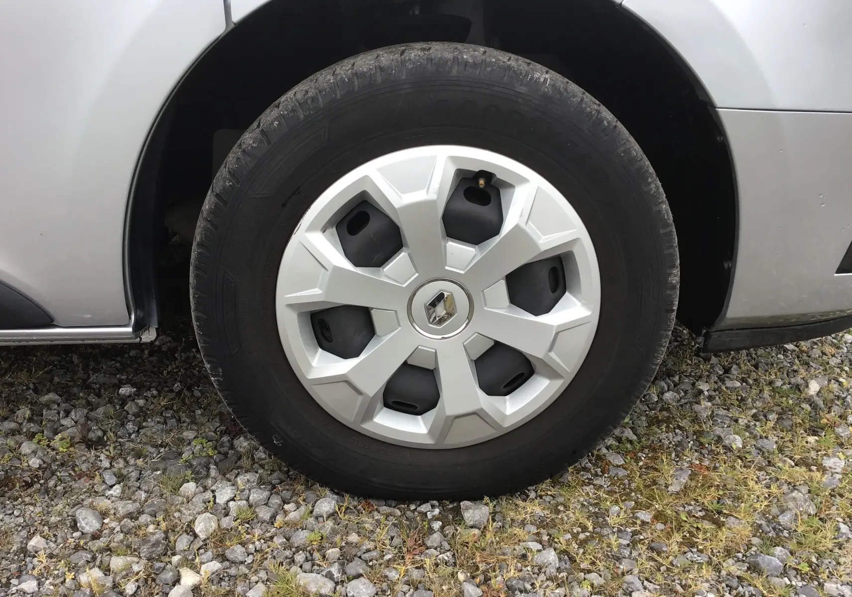 Gros plan sur la roue avant gauche d'un Renault Trafic Combi gris clair métal avec jante en plastique et logo Renault central.