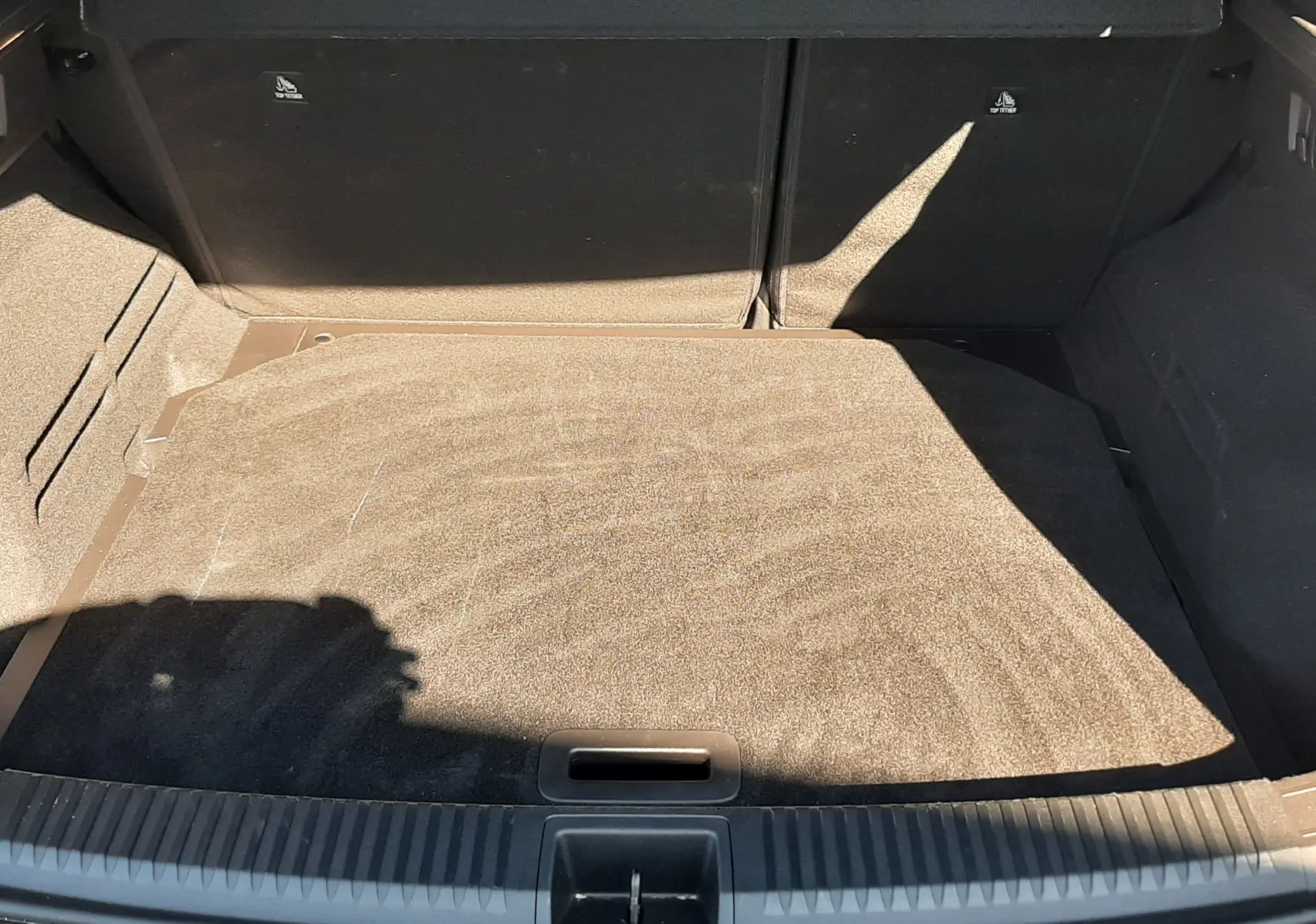 Coffre ouvert vu de l'arrière d'un Renault Austral gris schiste avec intérieur noir, montrant un espace de chargement vide.