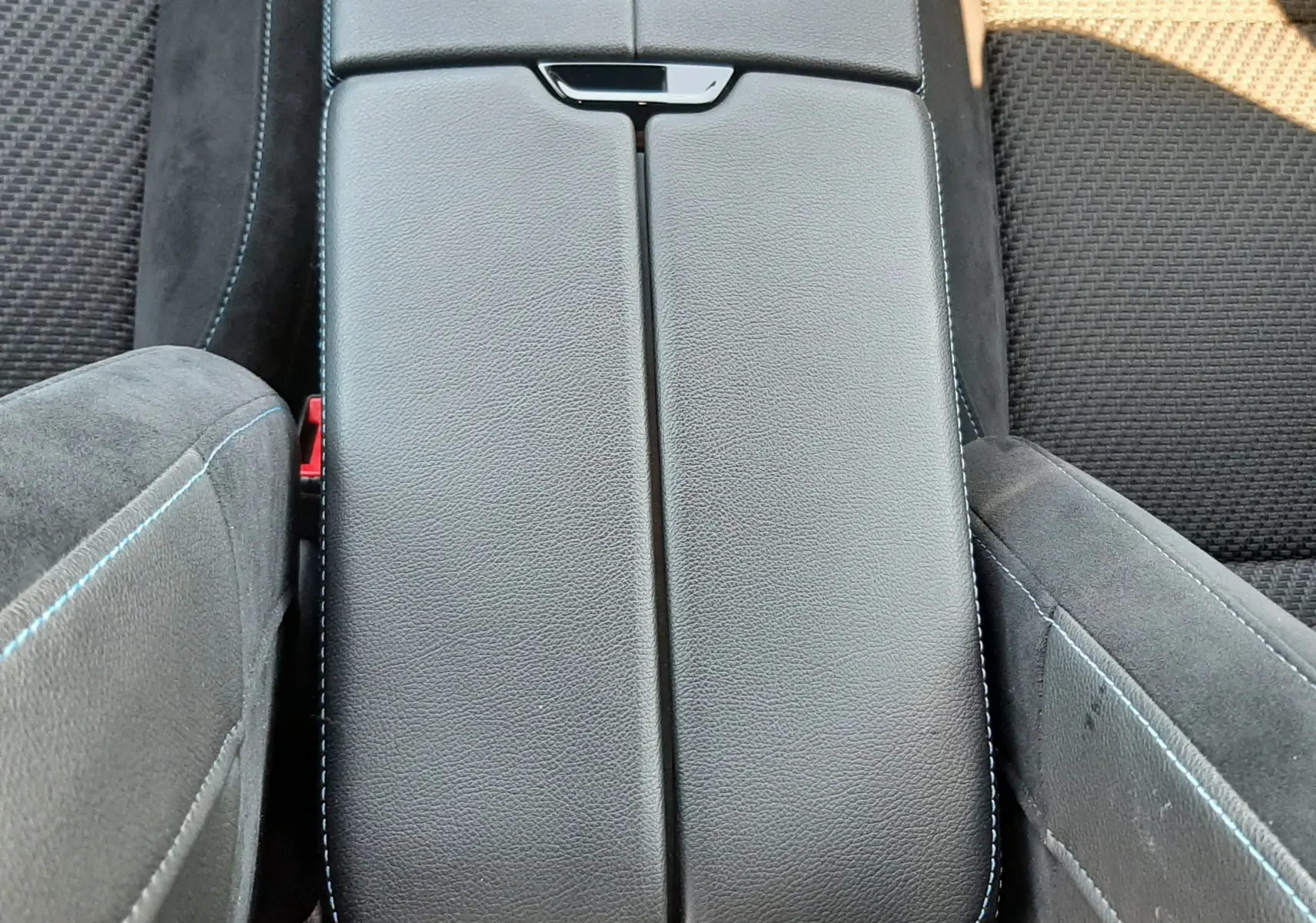 Vue plongeante sur la console centrale noire avec surpiqûres bleues, entre les sièges tissu gris foncé du Renault Austral 2025.