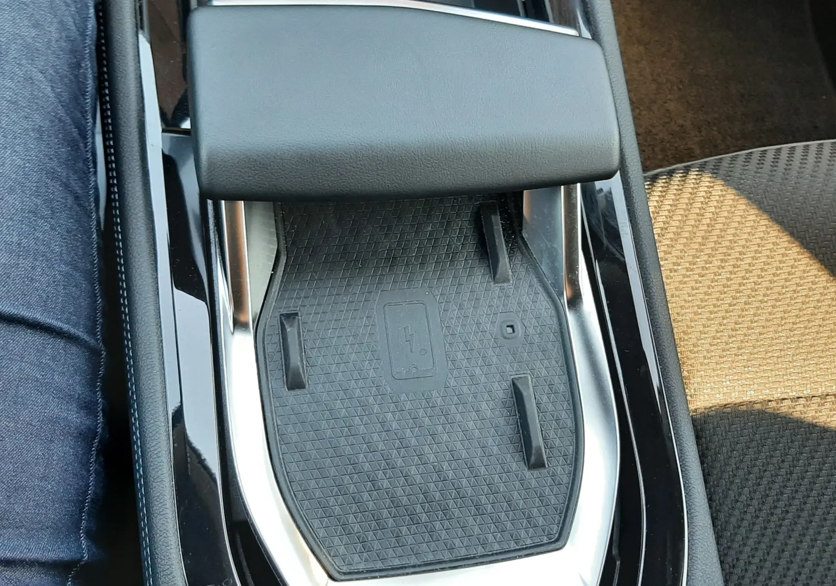 Gros plan sur la console centrale noire du Renault Austral 2025 avec repose-bras et surface de charge sans fil.