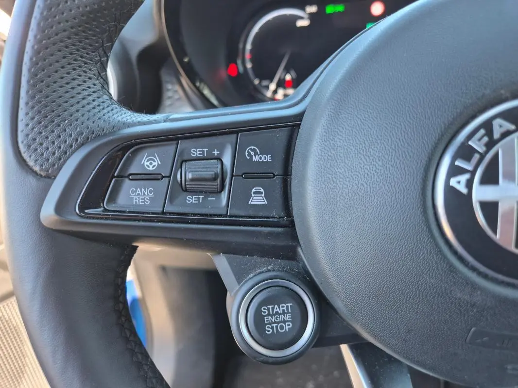 Gros plan sur le volant sport noir de l'Alfa Romeo Tonale 2025 avec commandes de régulateur et bouton start/stop.