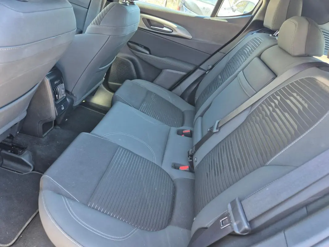 Vue intérieure arrière des sièges en tissu gris foncé de l'Alfa Romeo Tonale 2025, avec ceintures de sécurité visibles.