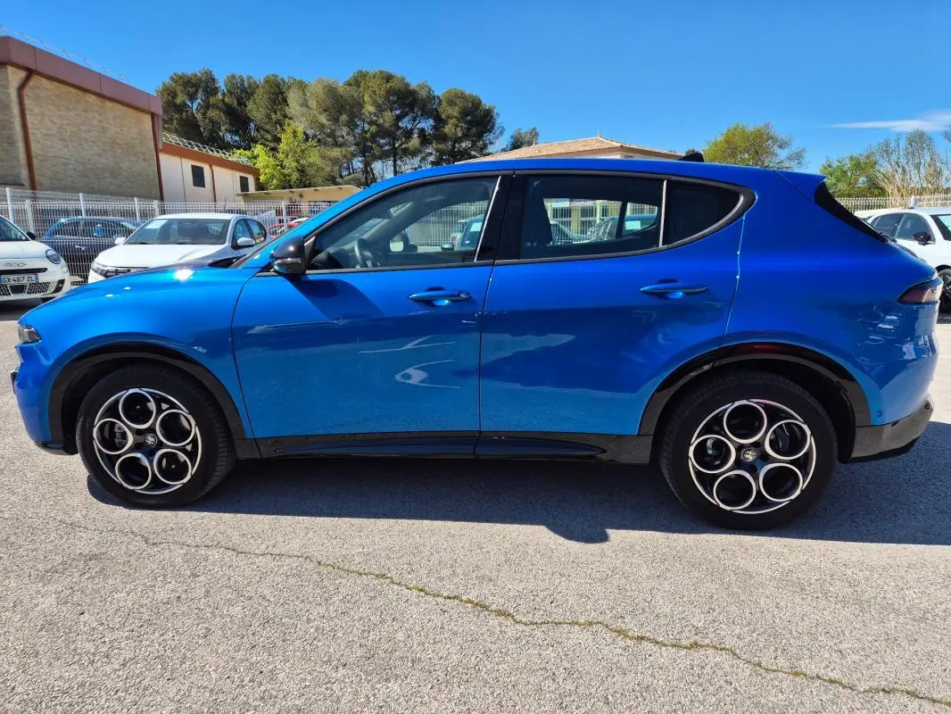 Vue de profil côté gauche d'une Alfa Romeo Tonale bleu vif avec jantes alliage 18 pouces sur parking extérieur.