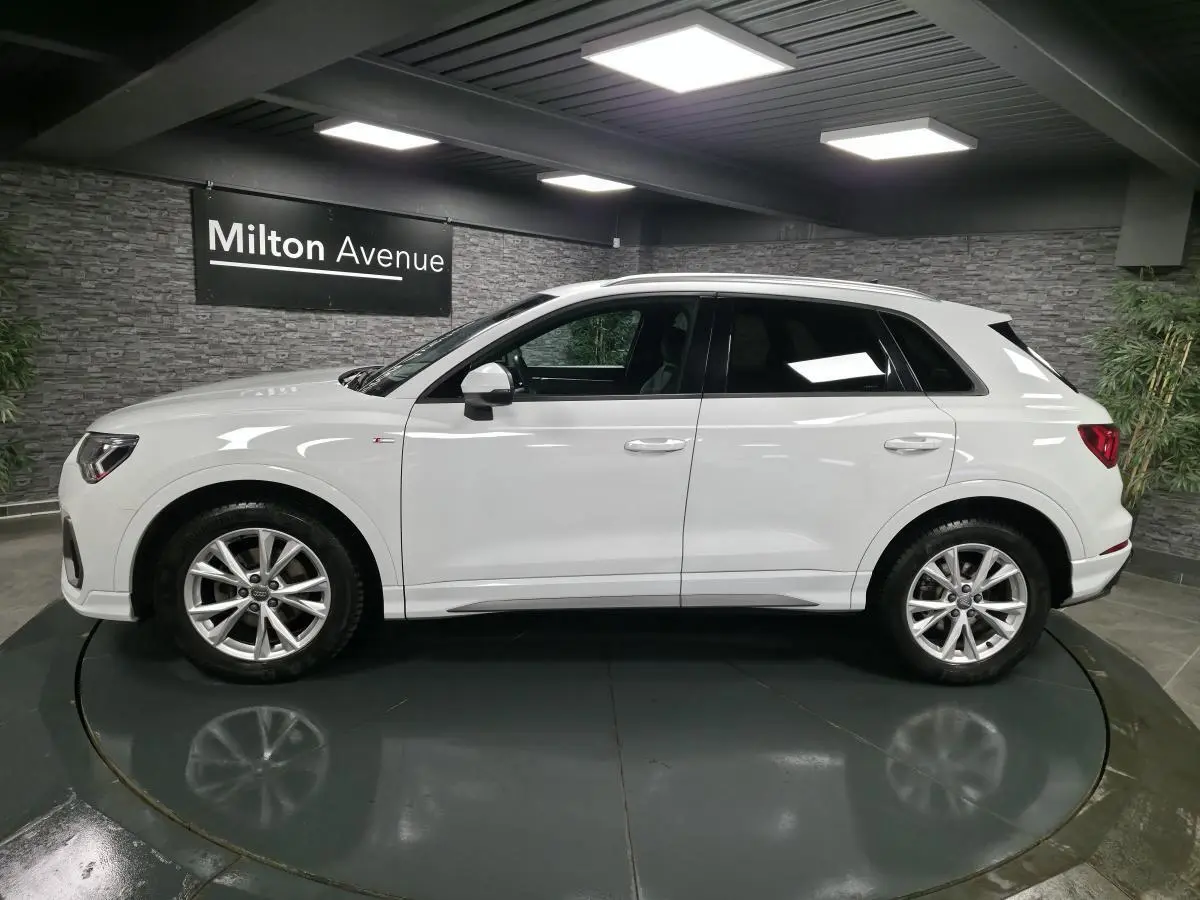 Audi Q3 blanc en vue de profil côté gauche, avec jantes alliage 5 branches doubles et vitres teintées.