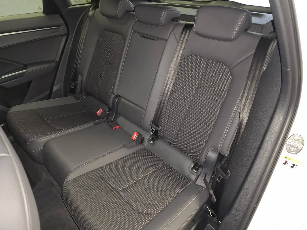 Vue intérieure sur les sièges arrière noirs en cuir et tissu du Audi Q3 blanc, avec ceintures de sécurité visibles.