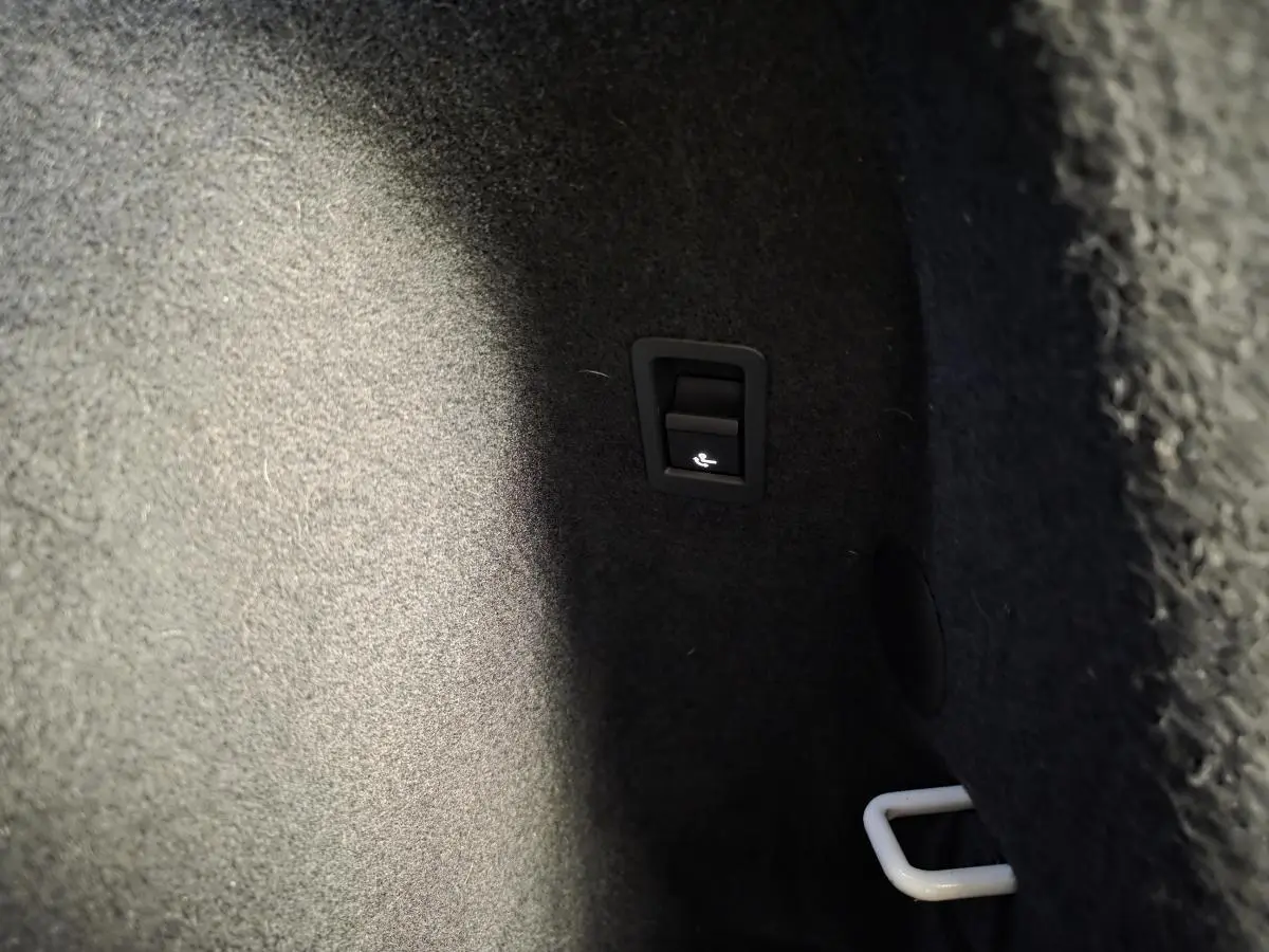 Détail du coffre d’Audi Q3 blanc 2019 montrant le levier d’ouverture de la trappe à skis.