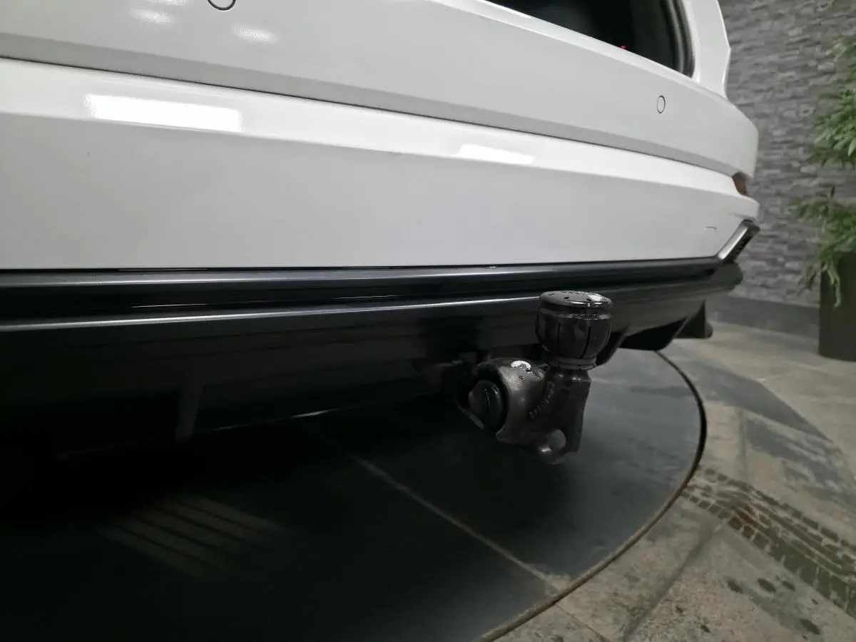 Gros plan sur le crochet d'attelage amovible à l'arrière d'un Audi Q3 blanc, finition S-Line, vue centrée.