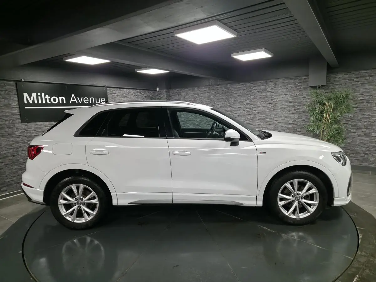 Vue latérale droite d'un Audi Q3 blanc 2019 S-Line avec jantes alliage 5 branches doubles dans un showroom.
