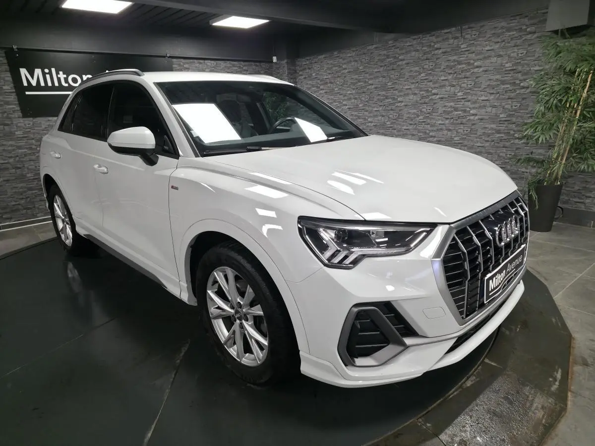 Audi Q3 blanc en vue 3/4 avant droit, avec calandre Singleframe noire et jantes alliage 5 branches doubles.