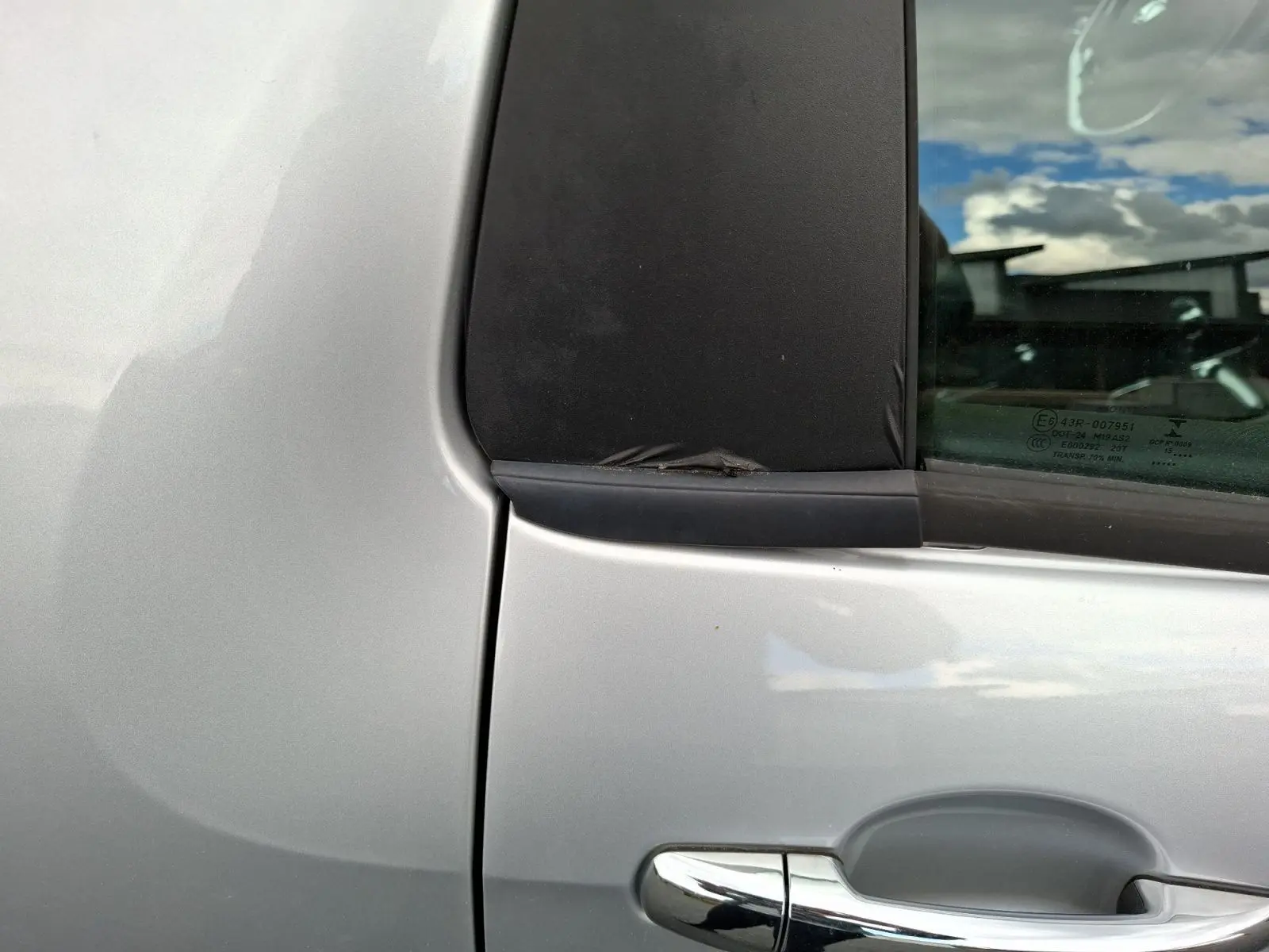 Détail de la poignée de porte côté gauche d'une Citroën DS3 gris clair avec fenêtre arrière surteintée.