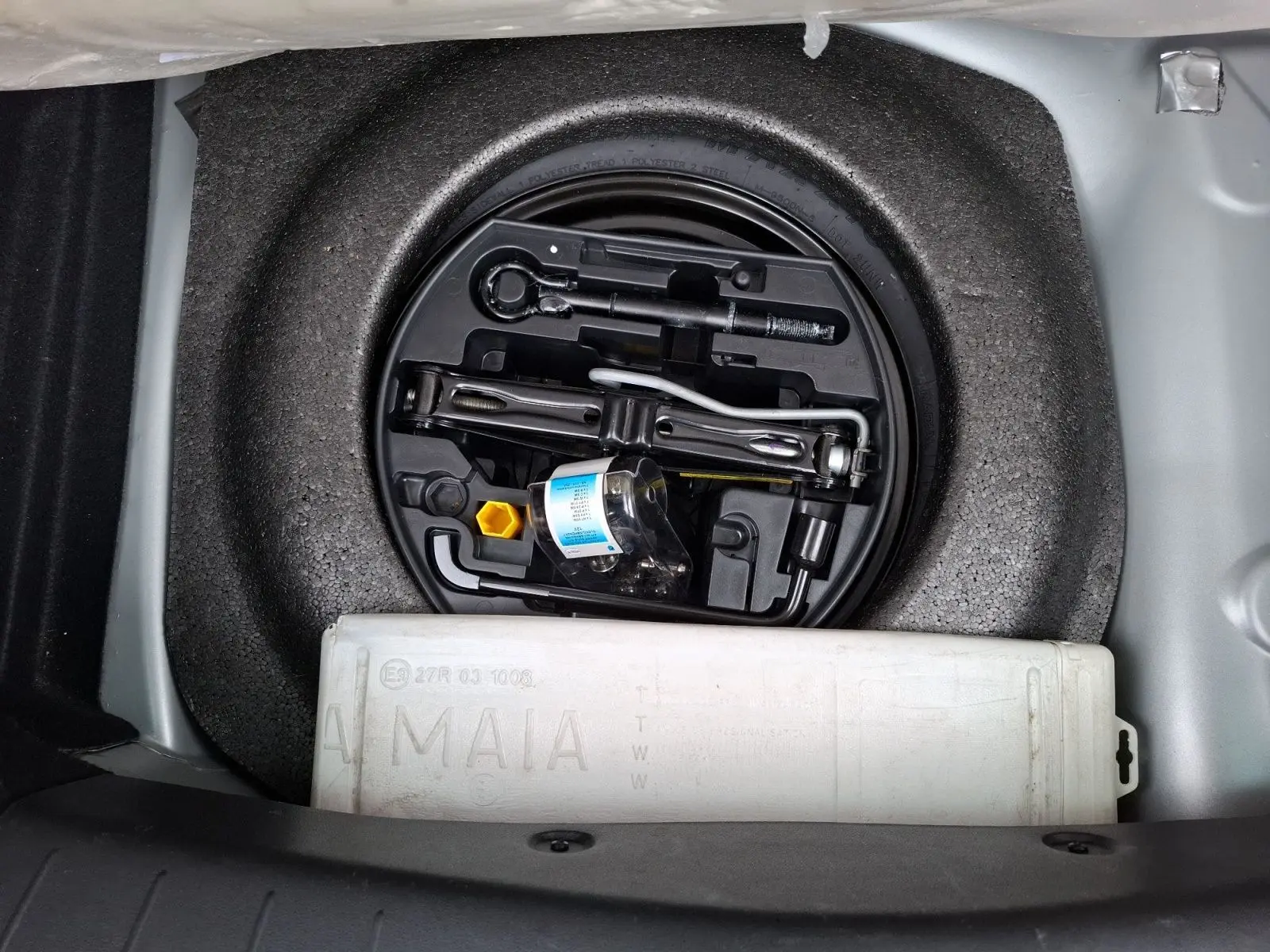 Vue plongeante sur le coffre ouvert d'une Citroën DS3 gris clair, montrant la roue de secours et les outils de bord.