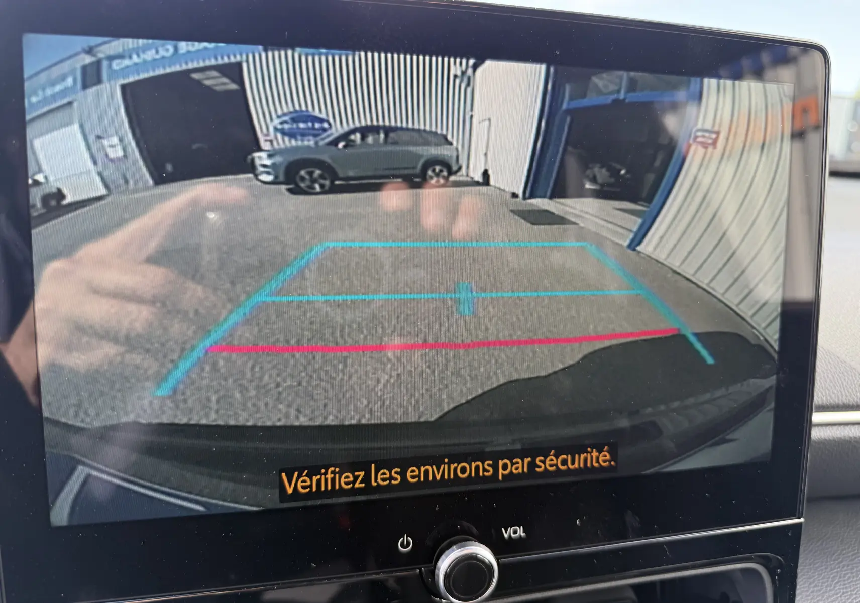 Vue caméra de recul montrant l’arrière du Toyota Yaris Cross gris atlas metal avec lignes de guidage bleues et rouges.