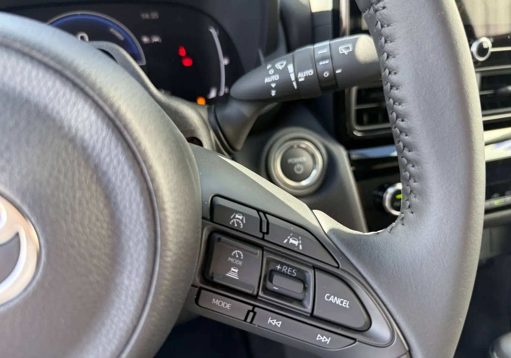 Gros plan sur le volant gris foncé du Toyota Yaris Cross 2026, montrant les commandes de régulateur et d’aide à la conduite.