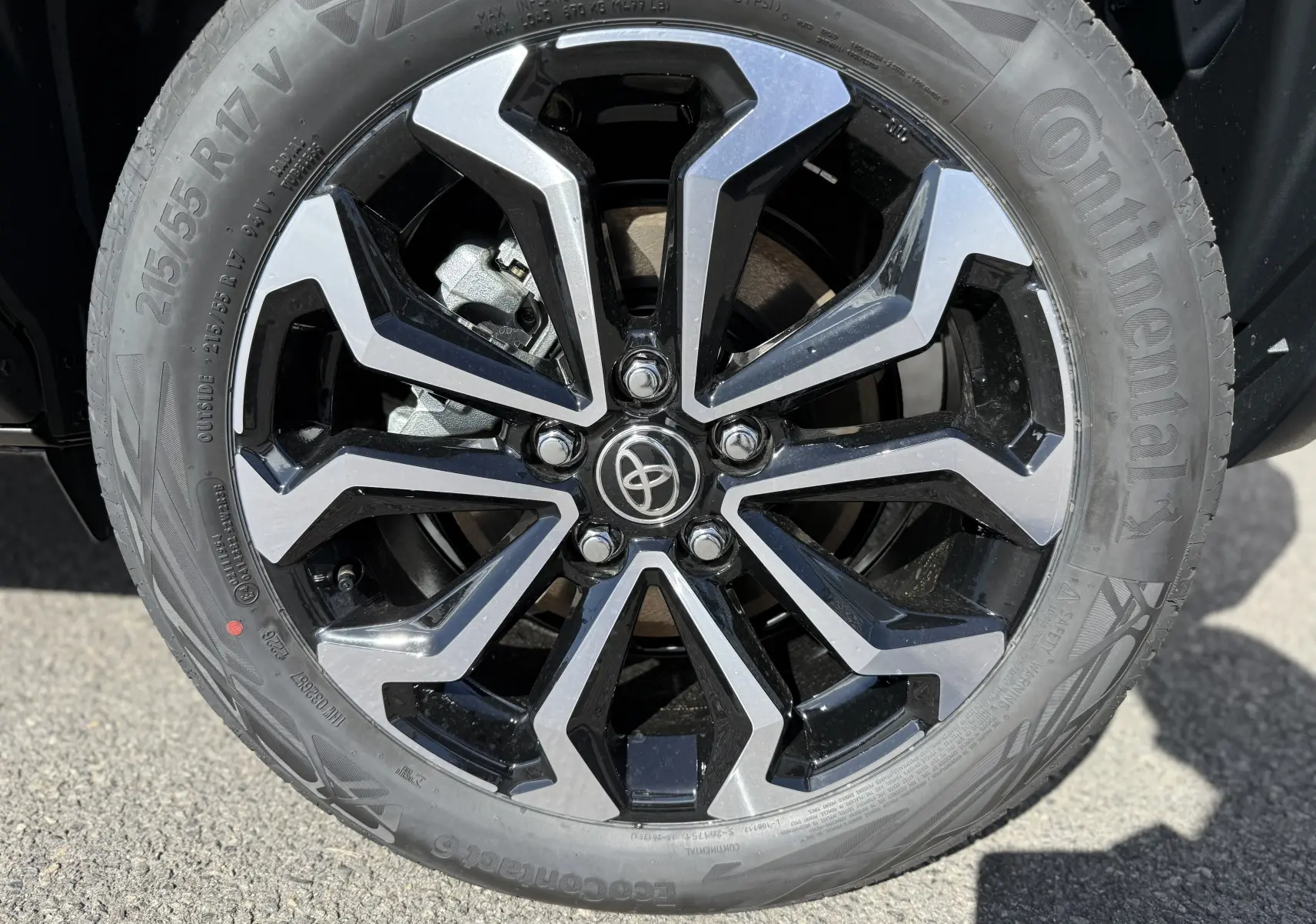 Gros plan sur la jante alliage bicolore noire et argentée du Toyota Yaris Cross gris atlas metal, pneu Continental visible.