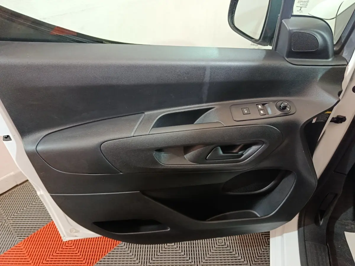 Vue intérieure côté gauche de la porte avant noire du Citroën Berlingo blanc, avec commandes électriques et poignée intégrée.