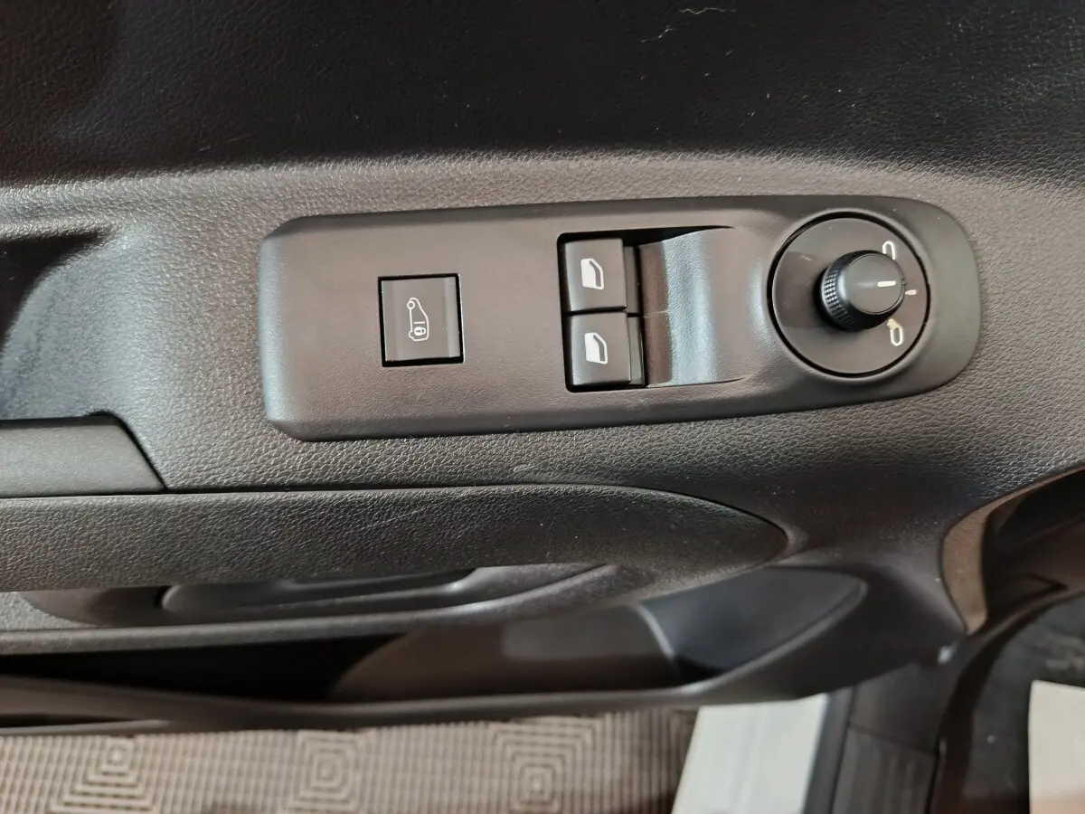 Gros plan sur les commandes de réglage des rétroviseurs et des vitres côté conducteur d’un Citroën Berlingo blanc.
