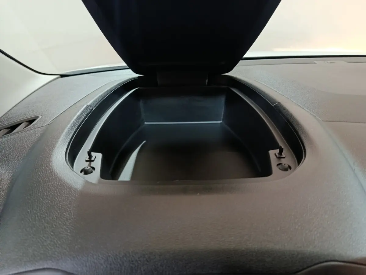 Vue rapprochée de la boîte de rangement ouverte sur le tableau de bord noir du Citroën Berlingo blanc 2021.