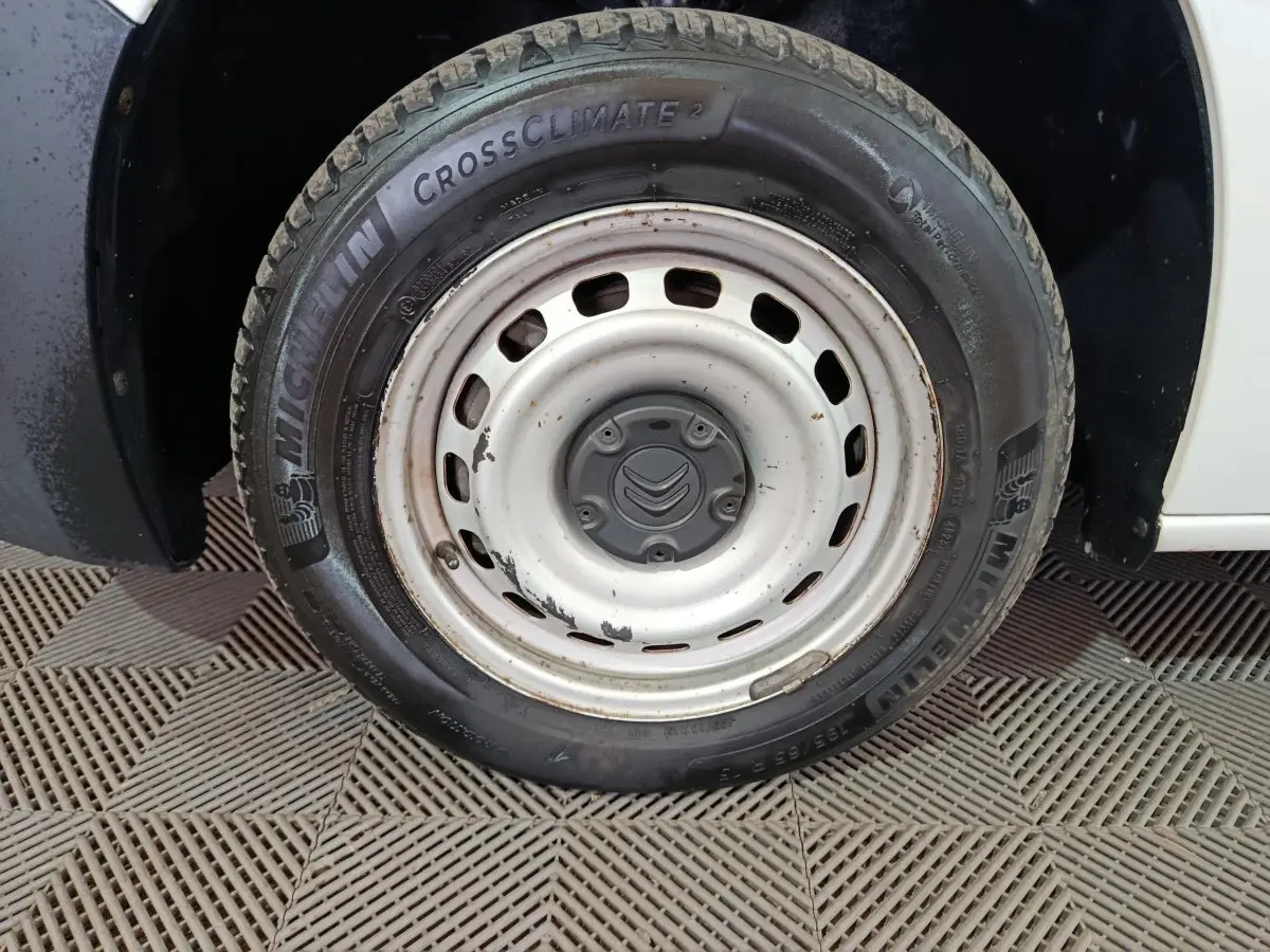Gros plan sur la roue avant droite blanche en acier avec pneu Michelin CrossClimate sur Citroën Berlingo blanc.