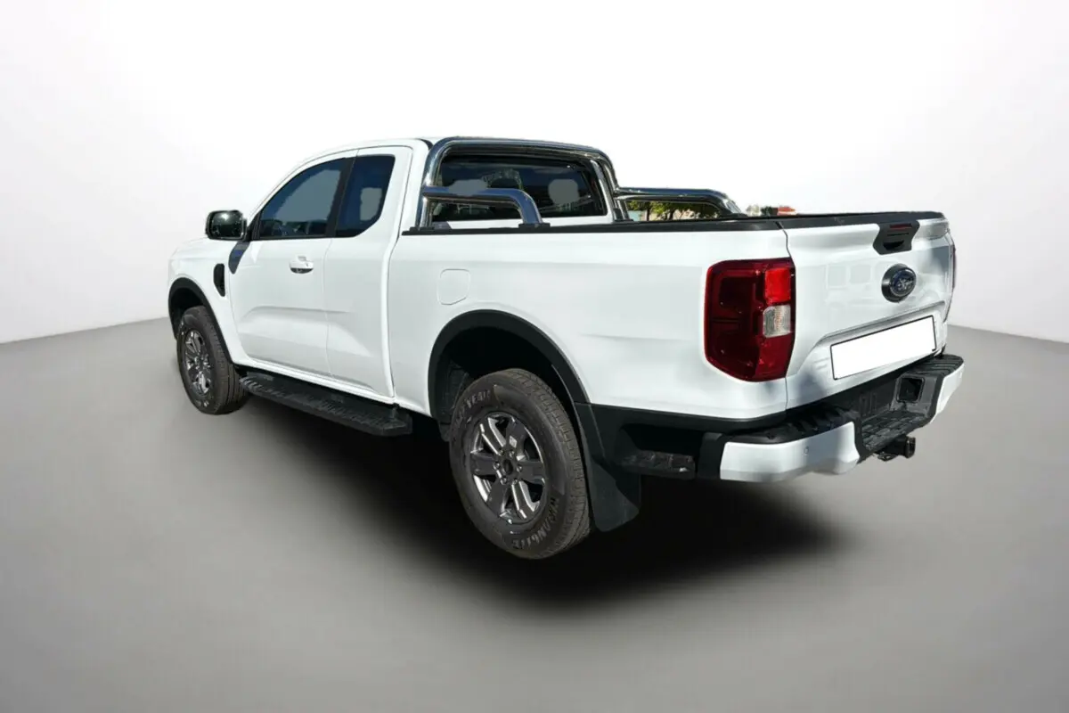 Ford Ranger blanc glacier en 3/4 arrière droit, avec arceaux inox et benne équipée d'un rideau coulissant.