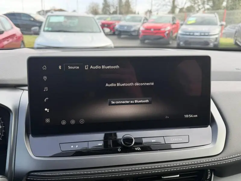 Vue intérieure centrée sur l'écran tactile du tableau de bord du Nissan Qashqai Hybrid e-POWER 2025, avec commandes audio visibles.
