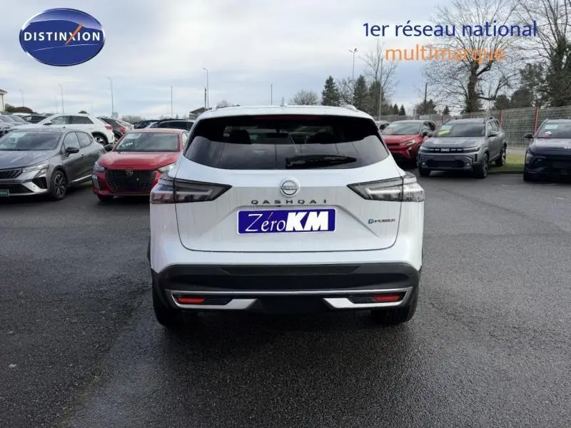 Vue arrière d'un Nissan Qashqai Hybrid e-POWER 2025 en blanc nacré avec logo et badge e-POWER visibles sur un parking.