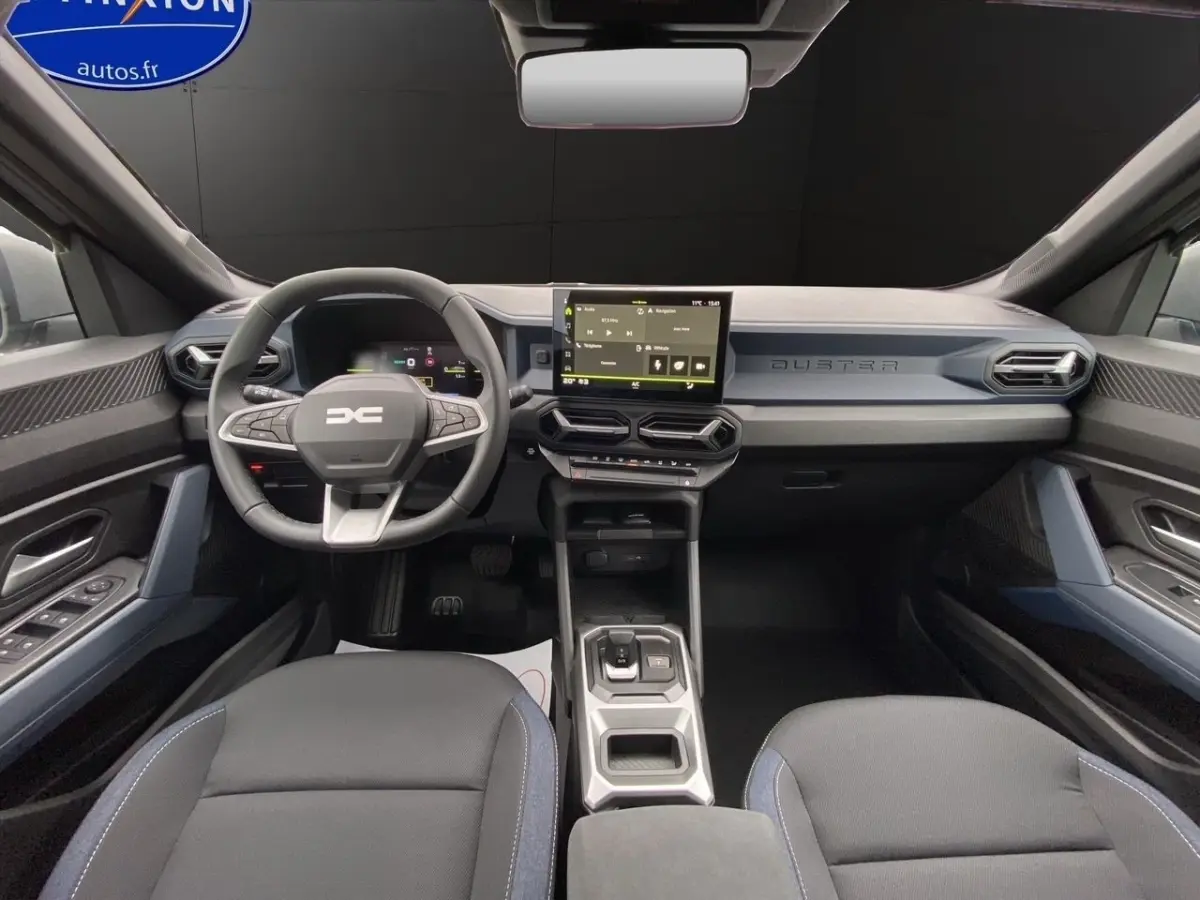 Vue intérieure avant du Dacia Duster gris foncé 2025, avec tableau de bord moderne et écran tactile central.