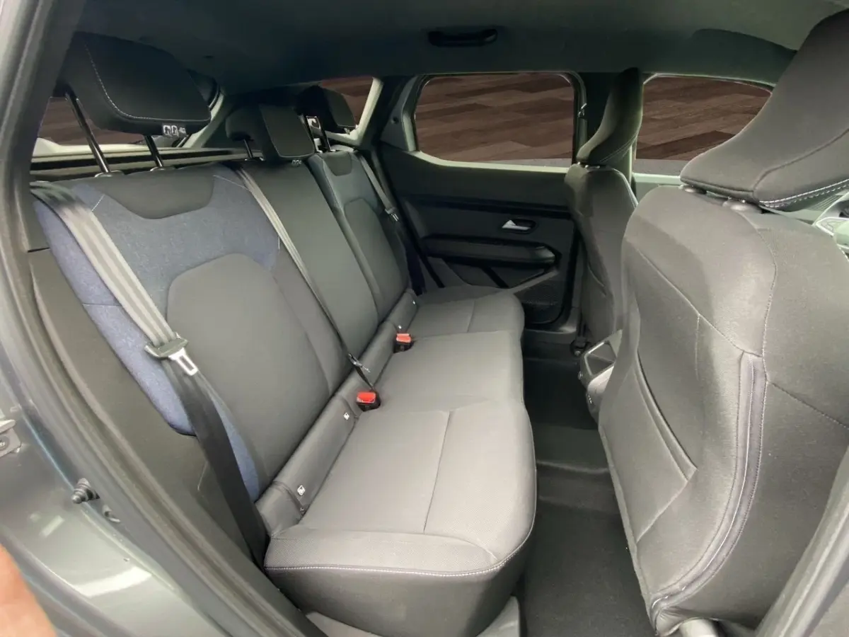 Vue intérieure côté droit sur la banquette arrière grise du Dacia Duster Journey Hybrid 140 2025.