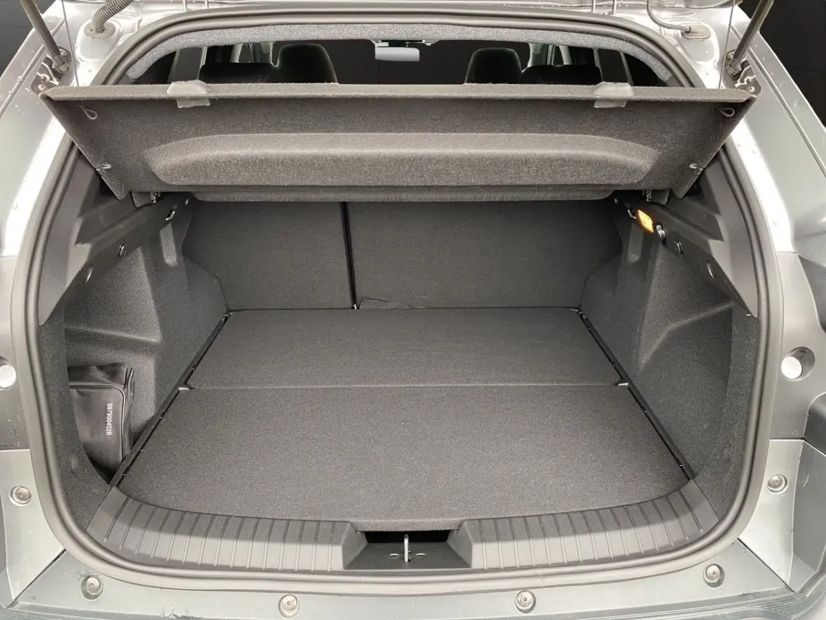 Coffre ouvert gris foncé du Dacia Duster Journey Hybrid 140, vue arrière montrant un espace de chargement plat et spacieux.