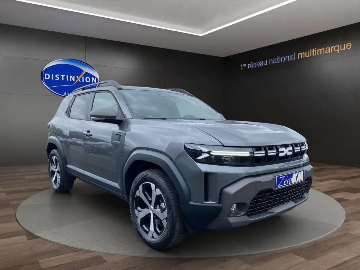 SUV Dacia Duster Journey Hybrid 140 gris foncé en 3/4 avant droit avec calandre et jantes distinctives.