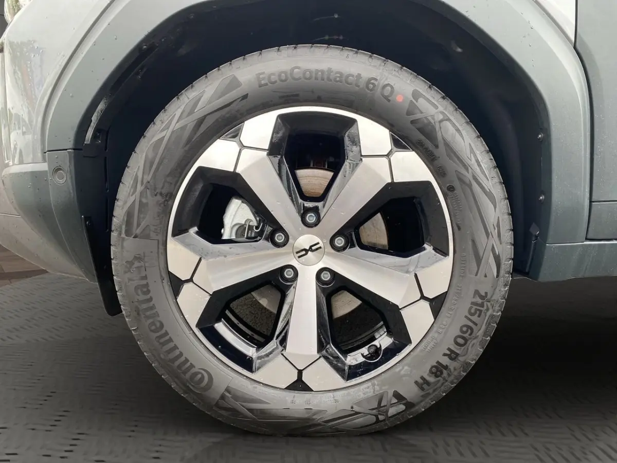 Gros plan sur la roue avant droite du Dacia Duster gris foncé, mettant en valeur la jante alliage bicolore et le pneu Continental.