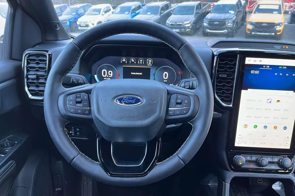 Vue intérieure centrée sur le volant cuir multifonctions et l’écran tactile du Ford Ranger blanc glacier 2025.